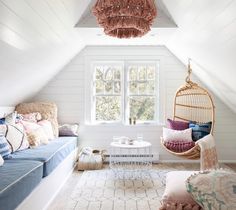 a living room filled with furniture and a hanging chair next to a window on top of a white wall