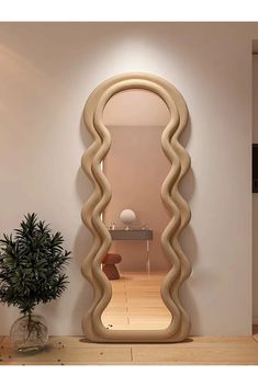 a large mirror sitting on top of a wooden floor next to a potted plant