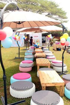 tables and stools are set up in the grass for an outdoor event with balloons on them