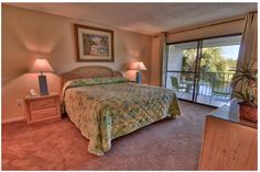 a bed sitting in a bedroom next to two lamps and a sliding glass door that leads to a balcony