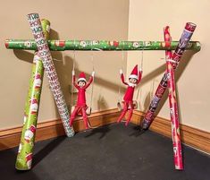 three elfs are hanging on a pole with christmas wrapping around them and some candy bars