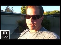 a man wearing sunglasses standing in front of a house with the sun shining on his face