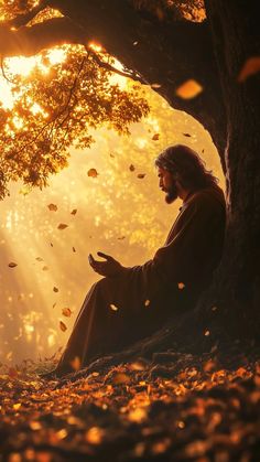 a man sitting under a tree in the middle of autumn with leaves flying around him