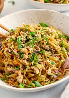 two white bowls filled with food and chopsticks on top of a table next to each other