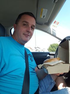 a man sitting in the back seat of a car eating a sandwich