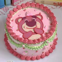 a pink and green cake with a teddy bear on it's face in the center