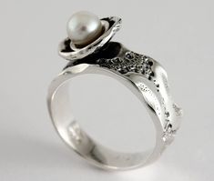 "Here is the ring \"Flower of sea\" in sterling silver and white freshwater pearl. Each ring is unique, the lace around the dome that hosts the pearl is unique each time and may be different from the photo. Size: 7 mm width (9/32 in) Material: Sterling silver and white freshwater pearl The unique texture of the ring is made from a molding of a sea urchin shell symbolizing a footprint of good times. This organic texture was handcrafted by the jeweler Marie-Eve Bordeleau of Trois-Rivières, Quebec, Canada. Included: -A polishing cloth -A bookmark about the collection -A rigid box ** Shipping fees are free in Canada and the United States Inspiration: The shell of the sea urchin inspires emotions, feelings and memories. The unique impressions left by the shells symbolize a true story, a trip or Unique Pearl Jewelry For Anniversary, White Pearl Sterling Silver Ring, White Sterling Silver Pearl Ring, Unique Sterling Silver Pearl Promise Ring, Elegant Sterling Silver Pearl Ring Stamped 925, Sterling Silver White Gold Pearl Ring With Pearl Drop, White Gold Pearl Drop Ring In Sterling Silver, Sterling Silver Pearl Drop Ring In White Gold, Unique Pearl White Jewelry For Wedding