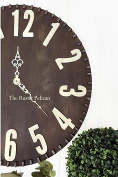 a clock that is on the side of a wall next to a potted plant