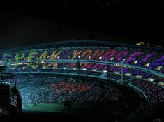 a large stadium filled with lots of people at night, lit up by bright lights