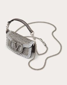 Valentino Garavani Locò micro chain bag with rhinestone appliqués and VLogo Signature element covered with Swarovski® crystals. Equipped with both a detachable sliding chain strap and a detachable handle, this accessory can be worn as a crossbody/shoulder bag or carried as a handbag. - VLogo Signature crystal-covered element - Palladium-finish hardware - Magnetic closure - Removable leather handle - Removable sliding chain shoulder strap - Leather lining. Interior: one card slot Shoulder strap d Valentino Bag, Micro Bag, Women's Bags By Style, Rhinestone Appliques, Chain Bag, Affordable Luxury, Chain Bags, Magnetic Closure, Leather Handle