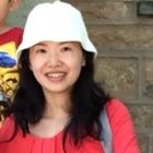 a woman in a red shirt and white hat with a boy standing behind her smiling at the camera