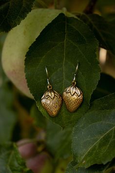 Solid (not plated) raw brass golden strawberries dangle from solid sterling silver ear hooks. These handcrafted brass strawberry earrings are very light weight and playful. A great way to get in the crisp mood of autumn.  A patina has been hand added and buffed to bring depth to the texture and add to the style. Be sure to check the rest of my fruit earrings and Jewelry! Comfortable and very light weight: Each Earrings weights approximately .04 oz (1.1g) each.  ✦ C A R E - I N S T R U C T I O N S ✦ Each creation is lovingly hand crafted with meticulous attention to detail, aesthetic, and durability. Please remember to remove your jewelry before bathing/showering, swimming, doing rigorous physical activities, or working with harsh soaps, lotions or any chemicals. Patinas change over time by Gold Earrings With Fruit Design For Gift, Gold Fruit Design Drop Earrings, Gold Drop Earrings With Fruit Design, Strawberry Earring, Berry Jewelry, Strawberry Jewelry, Strawberry Earrings, Tarnish Remover, Fruit Jewelry