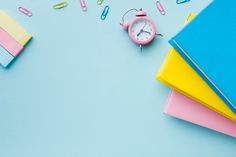 an alarm clock surrounded by school supplies on a blue background