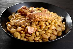 a black bowl filled with beans and meat