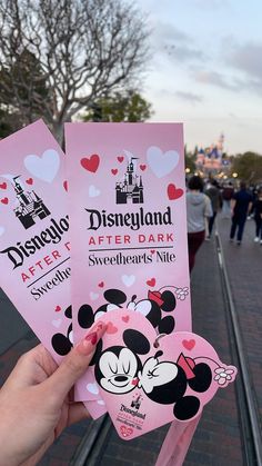 someone is holding up some pink disneyland after dark tickets for their trip to disney world