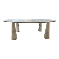 an oval marble dining table with three pillars on each end and a circular glass top