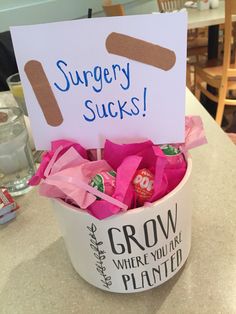 a bowl filled with candy sitting on top of a table next to a sign that says surgery sucks