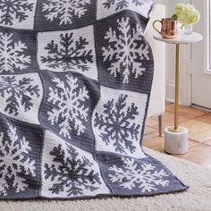 a crocheted blanket with snowflakes on it in the corner of a room