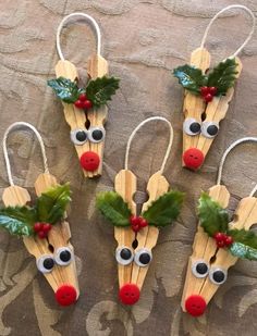 four popsicle reindeers with holly leaves and red noses are hanging on a wall