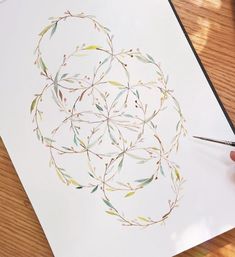 someone is drawing something with watercolors on the paper and it looks like leaves