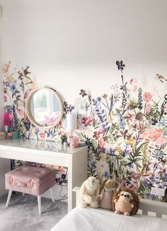 a bedroom with floral wallpaper and two stuffed animals in front of the mirror on the dresser