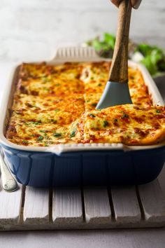 a spatula scooping cheese into a casserole dish