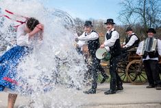 a group of men and women dressed in old - fashioned clothing splash water on each other