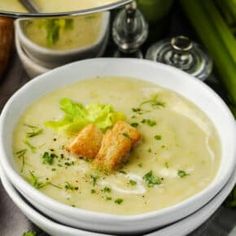 a bowl of soup with celery and bread croutons on the side