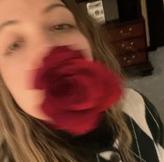 a blurry photo of a woman with a red rose in her mouth