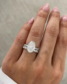 a woman's hand with a diamond ring on top of her finger and the other hand holding an engagement ring