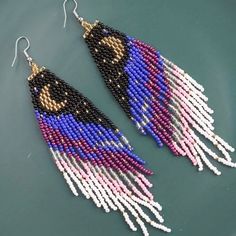 two pairs of beaded earrings with beads and fringes on top of a green surface