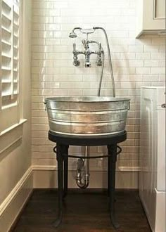 an old fashioned sink in the corner of a room with white brick walls and wood floors