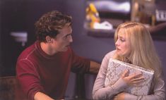 a man sitting next to a woman holding a book