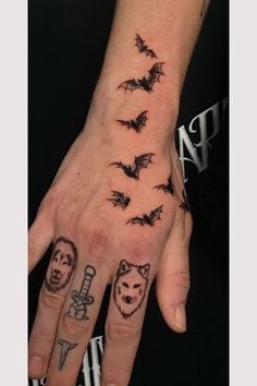 a person's hand with tattoos on it and some bats flying above the fingers