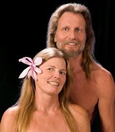 a man and woman with no shirts on posing for the camera, one is wearing a pink flower in her hair