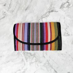 Our Wallet Shoulder Purse comes in several colors. Handmade and Fair Trade, this clever bag has a large zippered pocket, 9 credit card slots, a see-through ID slot, an interior pocket roomy enough for your checkbook, and even a loop to hold your pen! The long, corded strap can be hung over your shoulder or cross-body for added versatility. The Velcro closure keeps items secure. Guaranteed to be your new favorite bag! Bag: 7"W x 5"H (Folded) Strap: 52" 100% Cotton 1 Clear ID Pocket 9 Credit Card Multicolor Foldable Everyday Bags, Multicolor Bifold Bags For Everyday Use, Multicolor Clutch For Everyday Use With Mobile Phone Bag, Multicolor Bifold Travel Bag, Everyday Multicolor Foldable Bags, Foldable Rectangular Coin Purse For Travel, Everyday Multicolor Wallet With Zipper Pouch, Foldable Rectangular Wallet For Daily Use, Multicolor Wallets With Mobile Phone Bag For Everyday