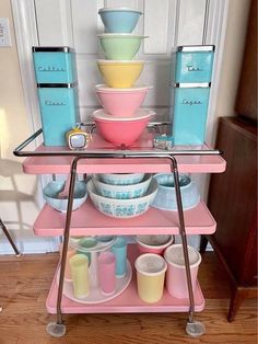 a pink cart with bowls and cups on it