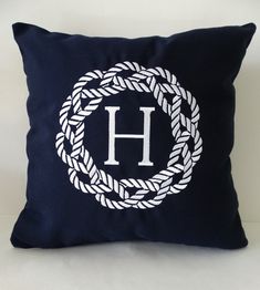 a blue pillow with a monogrammed h on it and a white rope around the letter h