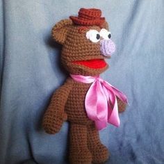 a crocheted stuffed animal with a pink ribbon around it's neck and nose