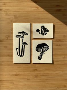 three black and white paintings on wood with mushrooms