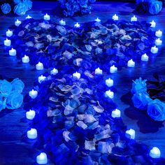 blue flowers and candles are arranged in the shape of a heart