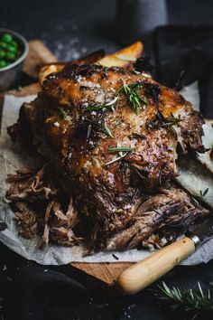 roast beef with herbs and garlic on a wooden cutting board next to some bread sticks