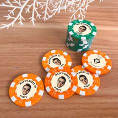 four orange and white poker chips sitting on top of a wooden table