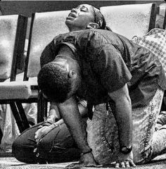 a man sitting on the ground with his head down next to another man who is leaning over him