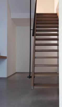 a wooden stair case next to a white wall