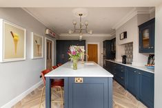 a large kitchen with blue cabinets and white counter tops, along with wooden flooring