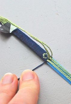 someone is holding a pair of scissors on a piece of string that has been stitched together