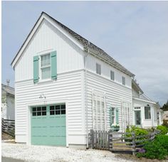 a white house with green shutters and a blue door