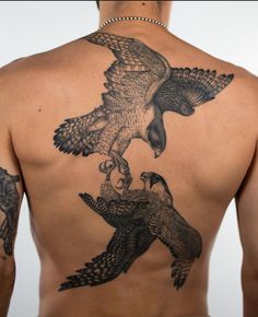 a man with an eagle tattoo on his back is looking at another bird in the air