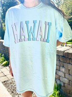 "Such a cute tee for summer! Comfort Colors chambray (light blue) t-shirt with \"HAWAII\" in blue and purple, with a black outline. Model is 5'4\" and wearing a size XL for an oversized look. 100% cotton." Graphic Tee Short Sleeve T-shirt, Graphic Crew Neck T-shirt, Light Blue Crew Neck Summer Top, Casual Light Wash T-shirt With Graphic Print, Casual Light Wash Short Sleeve T-shirt, Light Wash Graphic Tee With Graphic Print, Trendy Light Wash T-shirt For Summer, Light Blue Graphic Print Top For Vacation, Trendy Blue Pre-shrunk T-shirt